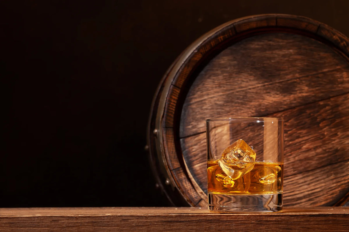 Rumglas mit Eis vor einem Holzfass